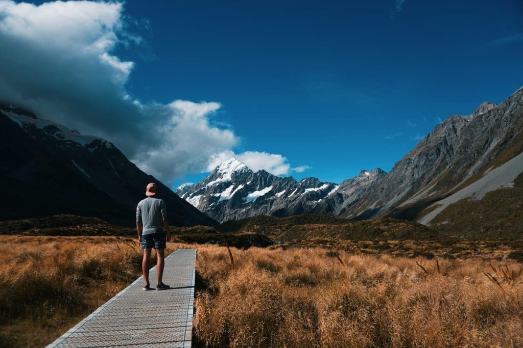 A man walks along a boardwalk at the base of Mount Cook in New Zealand.