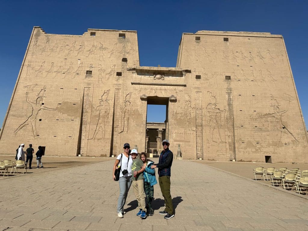 A family of four stands together in front of an ancient site near Luxor, a must on this 2-Week Egypt Itinerary for Families.