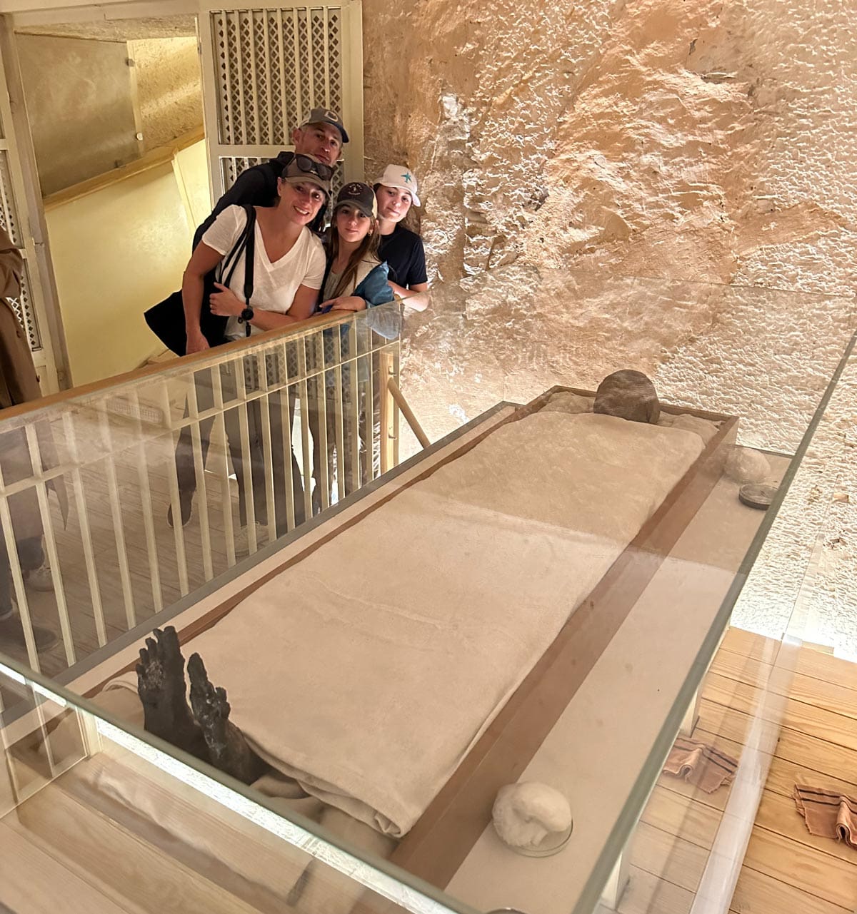 A family of four poses with a mummy on display at the Luxor Museum.