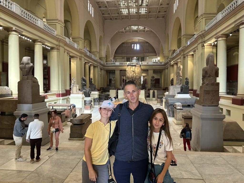 A dad and his two kids pose together inside a museum in Cairo.