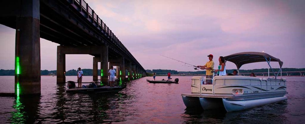 A boat fishes near a bridge on Buggs Island Lake/John H. Kerr Reservoir, one of the best lake destinations in Virginia with kids.