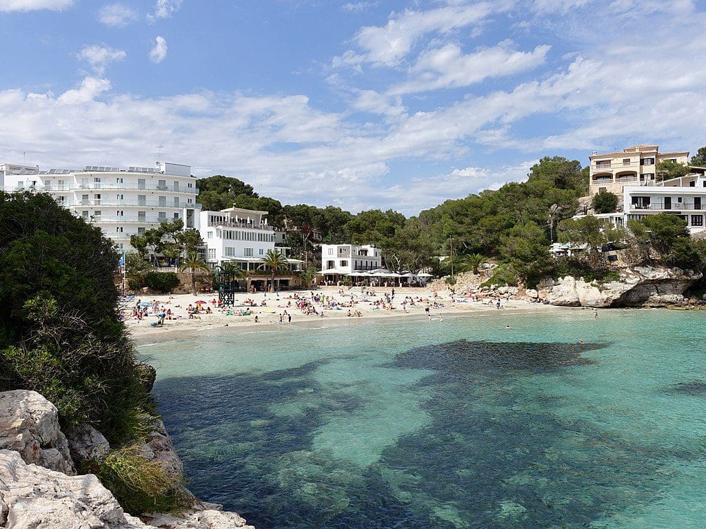 Cala Santanyi with clear waters and hotels in the distance.