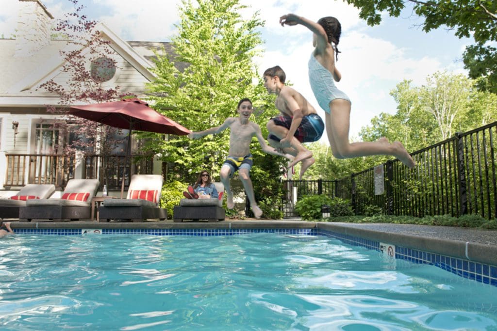 Three kids jump into the outdoor pool at Hidden Pond.
