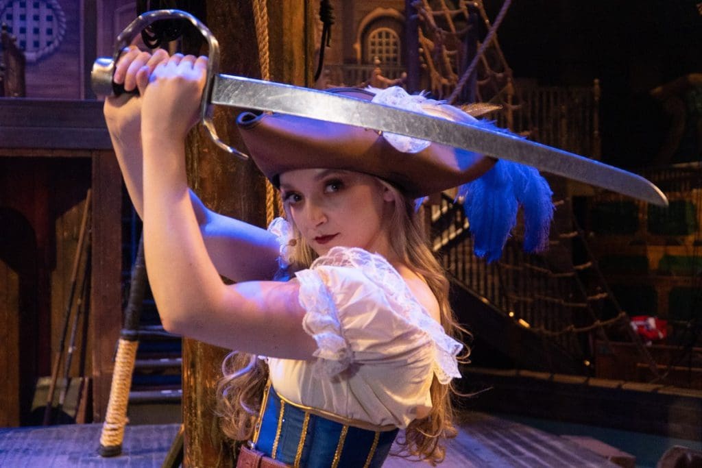 An actress in a pirate costume on stage at Pirates Dinner Adventure.