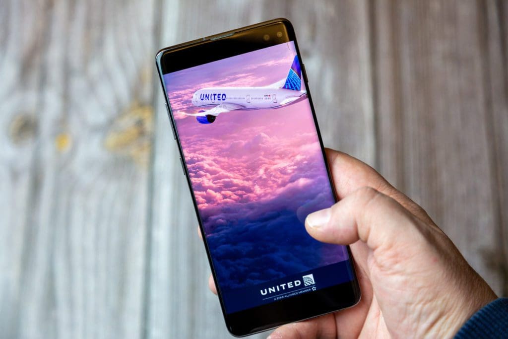 A hand reached out to navigate the United Airlines app on a smart phone.