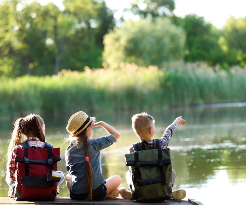 Three kids sit together at the edge of a dock, looking out onto one of the best lakes in Virginia.