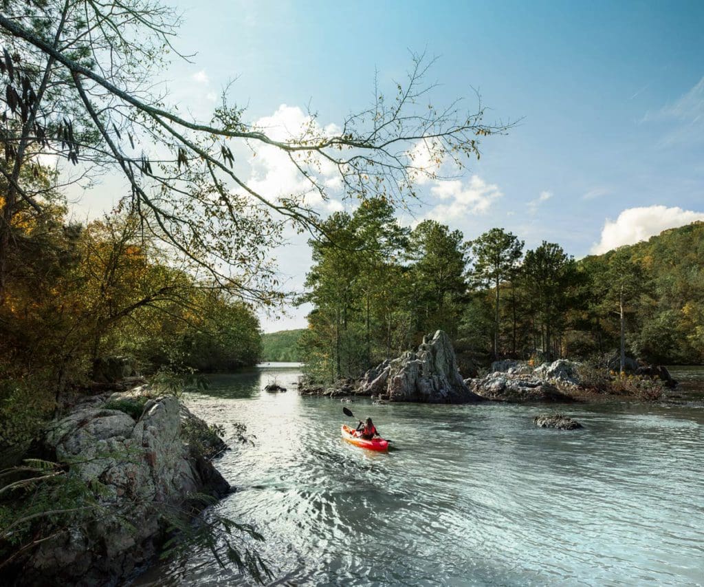 A kayaker enjoys a lovely paddle on Badin Lake in North Carolina, one of the best lakes in North Carolina for a family vacation.