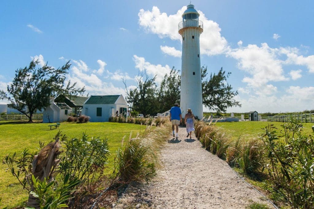 A couple walks toward the Grand Turk Lighthouse on a sunny day, one of the best things to do in Turks & Caicos with kids.