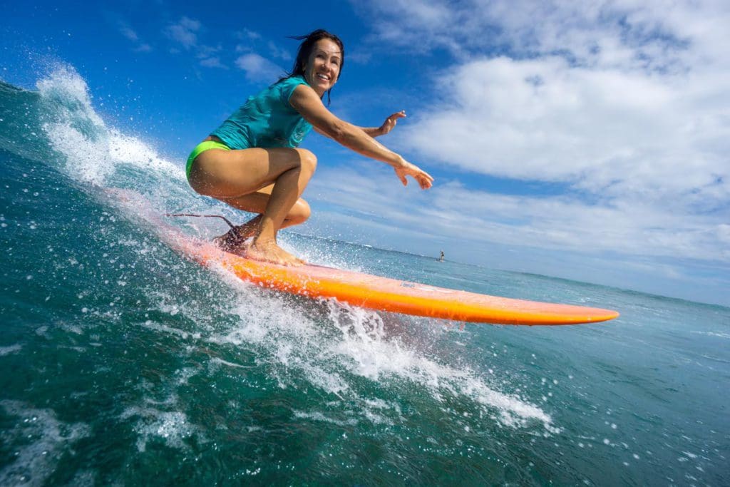 A teen girl on a surf board catching a wave. Surfing with kids is easy when you have a great surfboard! 