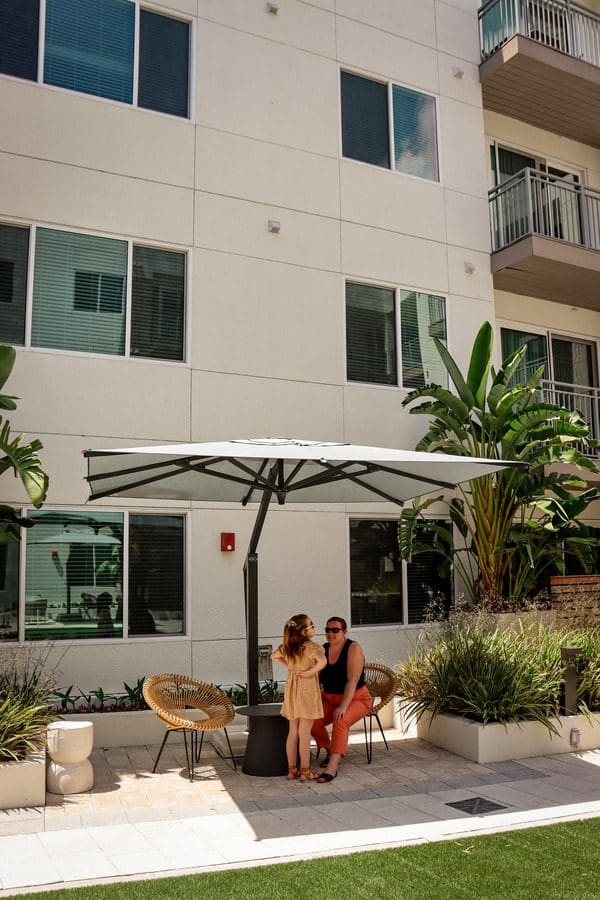 A mother and her daughter enjoy a shady spot in the beautiful courtyard at AVE Tampa Riverwalk.