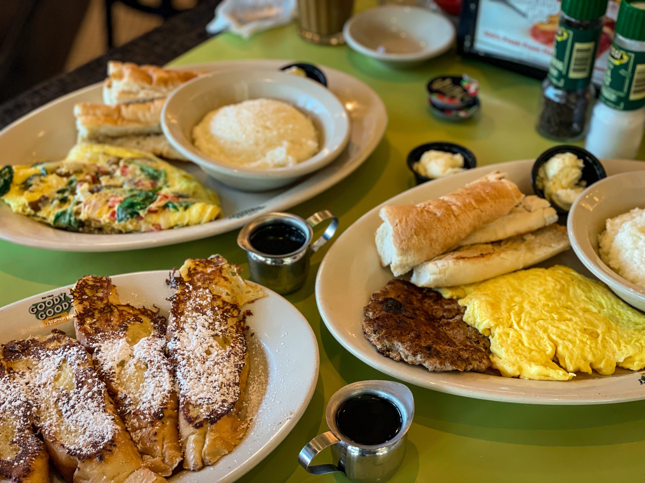 A spread of breakfast food at Goody Goody Burgers in Tampa Bay, including French toast, grits, and omelettes.