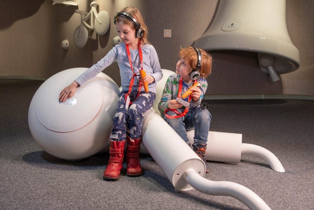 Two kids listen to headphones at an exhibit in AUDIOVERSUM ScienceCenter, one of the best things to do in Innsbruck with kids this winter.