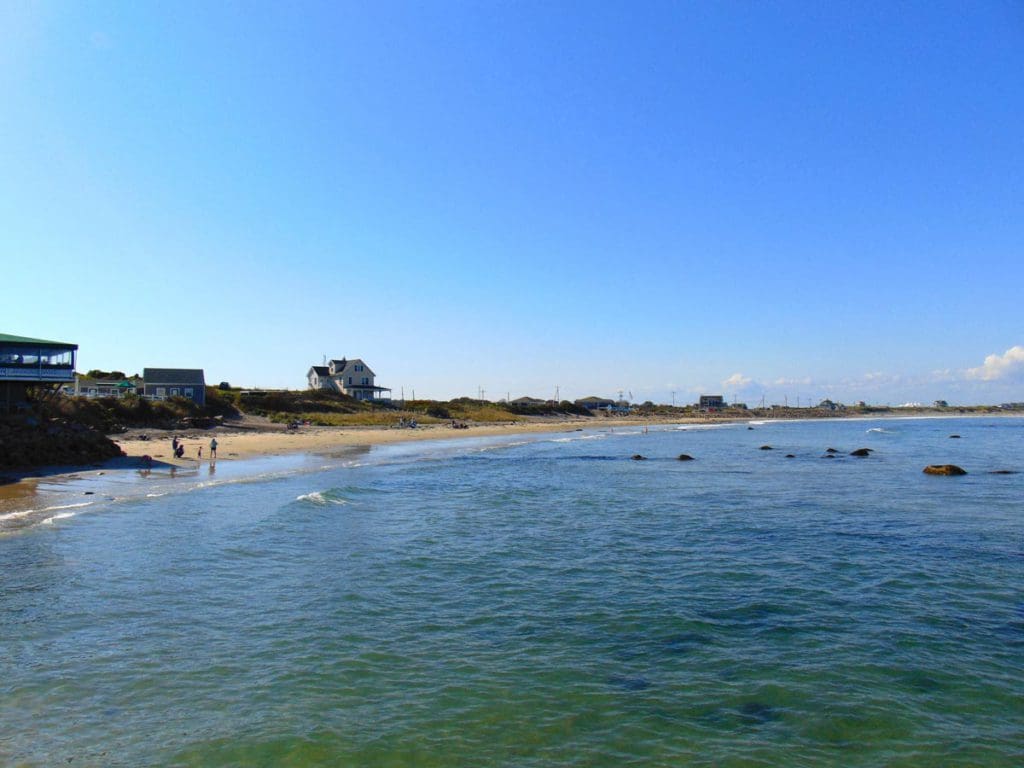 A view of a beach on Block Island with kids playing on the beach and houses in the background.