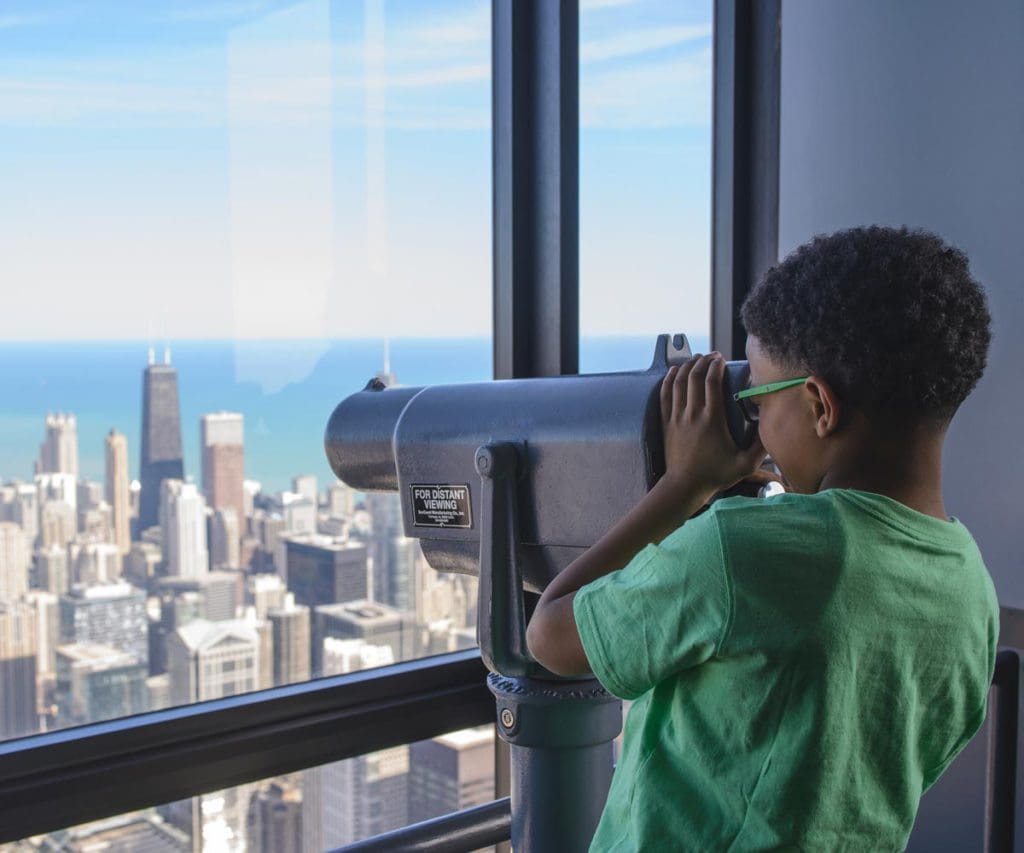 A young African American boy uses a view finder to look out on the Chicago skyline from the Skydeck.