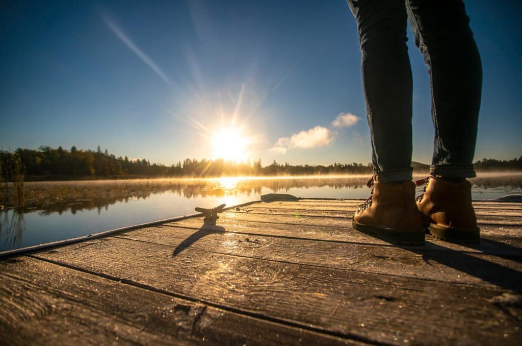 A person walks along a dock at sunrise on Cross Lake, one of the best lakes in Minnesota for families.