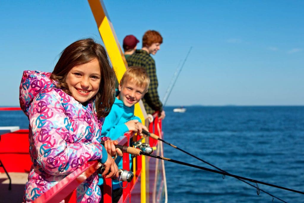 A family enjoys a fishing charter experience on Mille Lacs Lake, one of the best lakes in Minnesota for families.