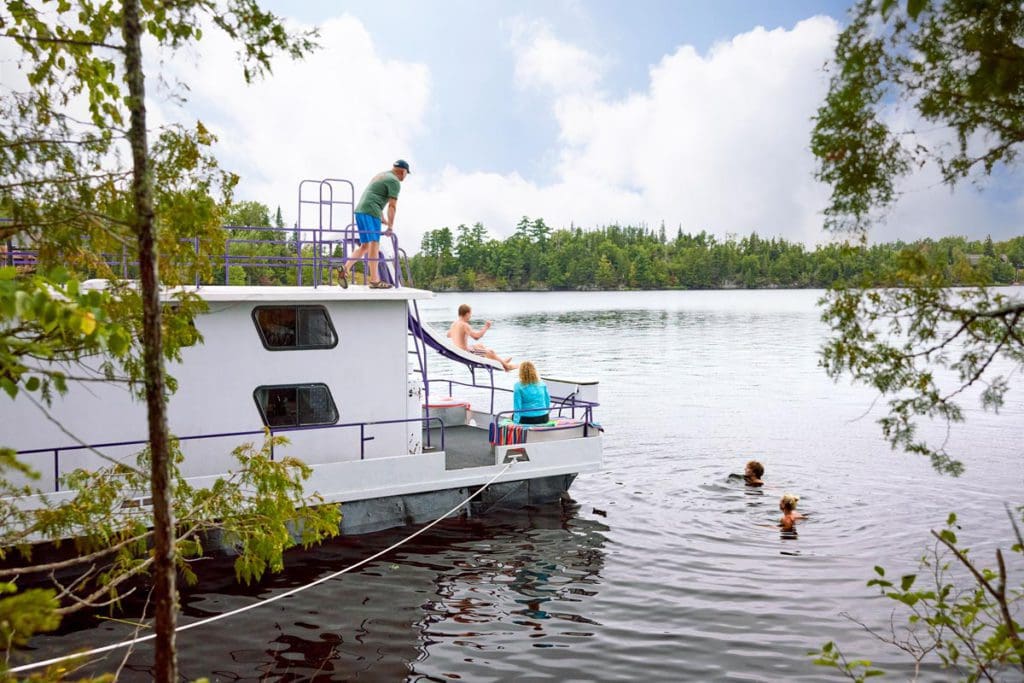 A family enjoys a tour around Rainy Lake on a houseboat on one of the best lakes in Minnesota for families.