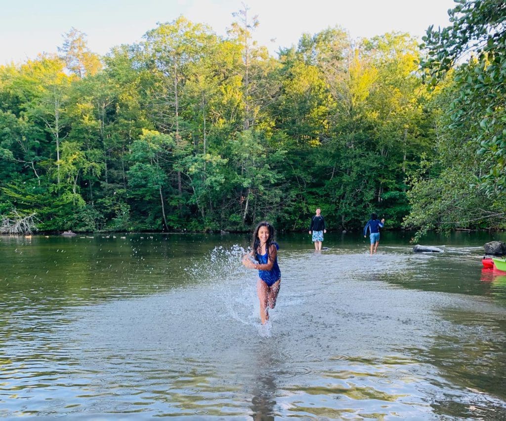 A young girl runs through shallow waters along the shore of Highland Lake.