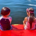 Two kids sit together at the edge of a lake inflatable while enjoying a sunny day at Highland Lake in Connecticut.