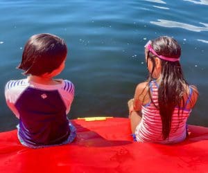 Two kids sit together at the edge of a lake inflatable while enjoying a sunny day at Highland Lake in Connecticut.