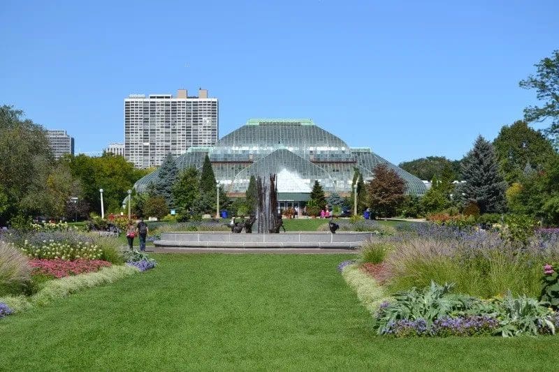 A verdant green lawn with the Lincoln Park Conservatory in the distance.