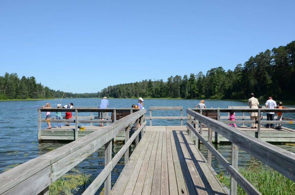 A large dock extends into Lake Itasca, where several people are fishing or taking in the views on one of the best lakes in Minnesota for families.