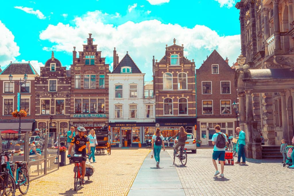 People meander on foot and by bike in one of the main squares of Delft, one of the best places to visit in the Netherlands with kids.