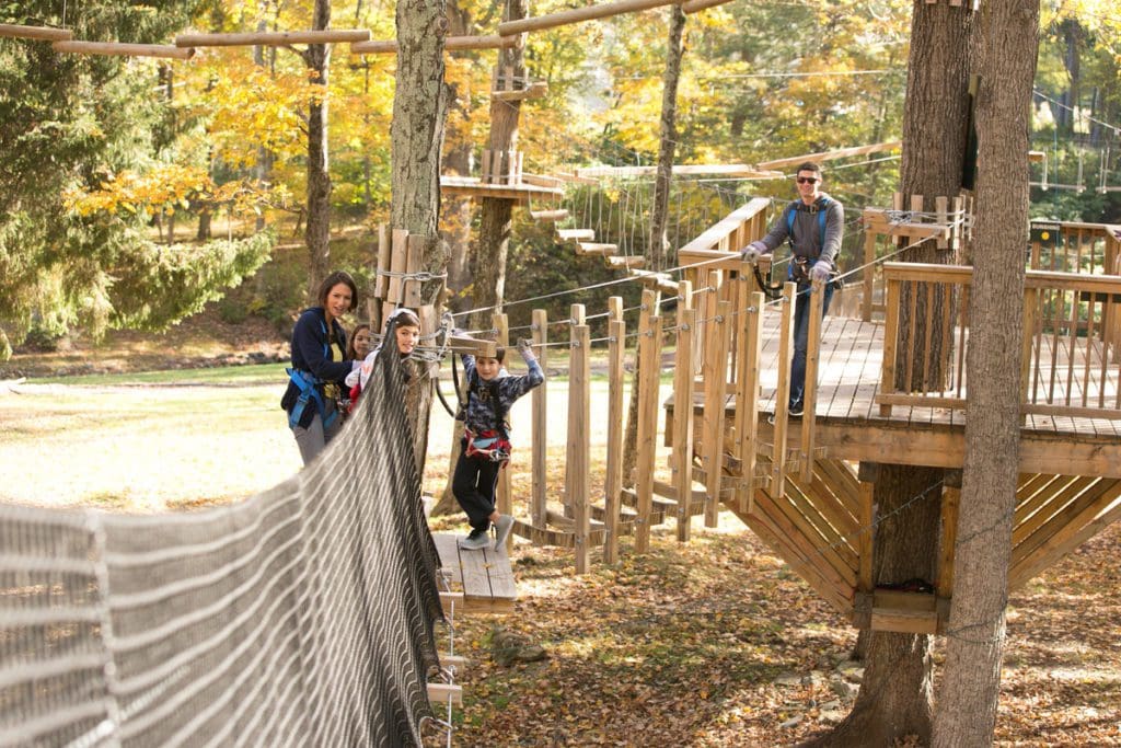 A family of five enjoys the treetops while on a ropes course in the Pocono Mountains.