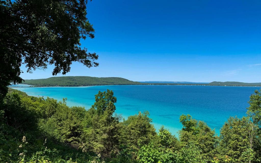 Through the trees, Big Glen Lake shimmers on a sunny day at one of the best lakes in Michigan for a family vacation.