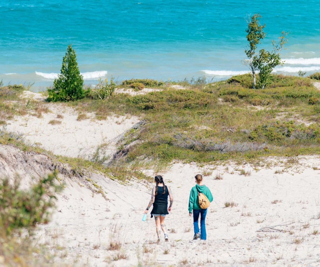 Two kids walk down a sandy path toward Lake Huron.