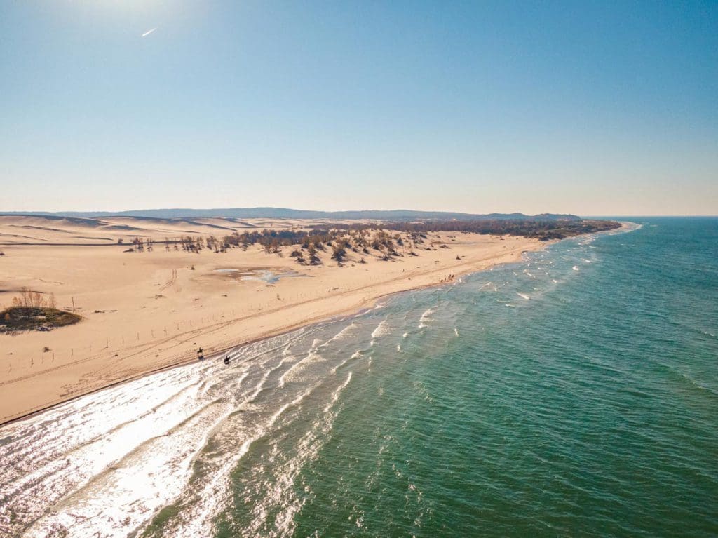 An aerial view of the long stretch of sandy beach along Silver Lake, one of the best lakes in Michigan for a family vacation.