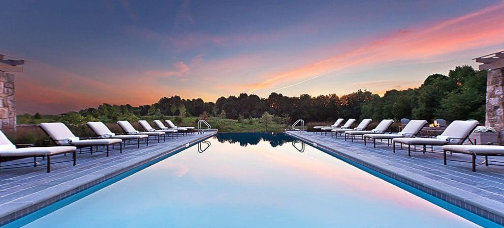 The lovely outdoor pool at Salamander Middleburg Resort & Spa, with a sunset over the treeline.