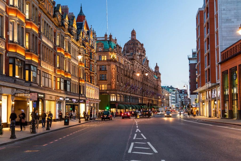 A vibrant London street in the Knightsbridge neighborhood lit up at night.