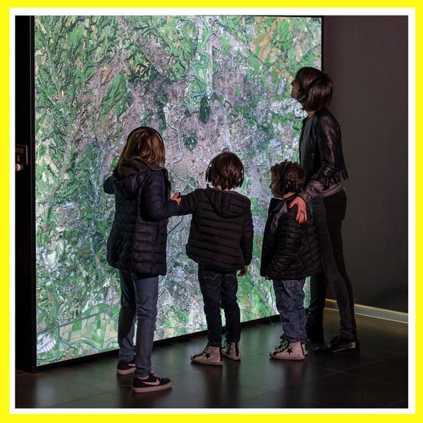 A mom and her through kids look at an exhibit at Welcome To Rome, one of the best museums in Rome with kids.