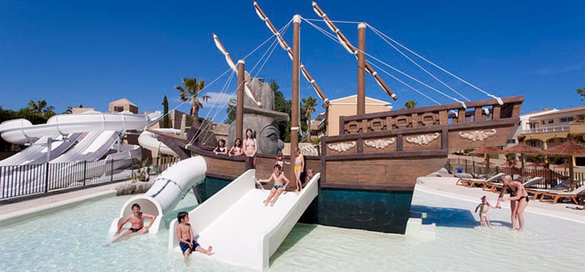 Kids playing and using the small slides at the pirate-themed outdoor water playground and pool at Insotel Cala Mandia Resort & Spa, one of the best all-inclusive hotels in Mallorca for families.