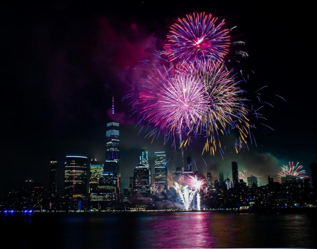 Fourth of July fireworks going off over the New York City skyline, one of the best places to celebrate fourth of July in the US for families.