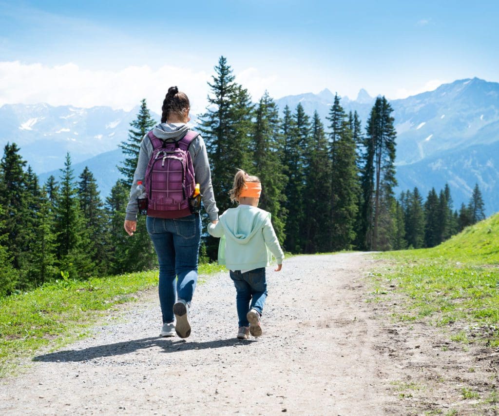 A mom and her young daughter trek along a mountain trail, while exploring one of the best destinations in Austria with kids.