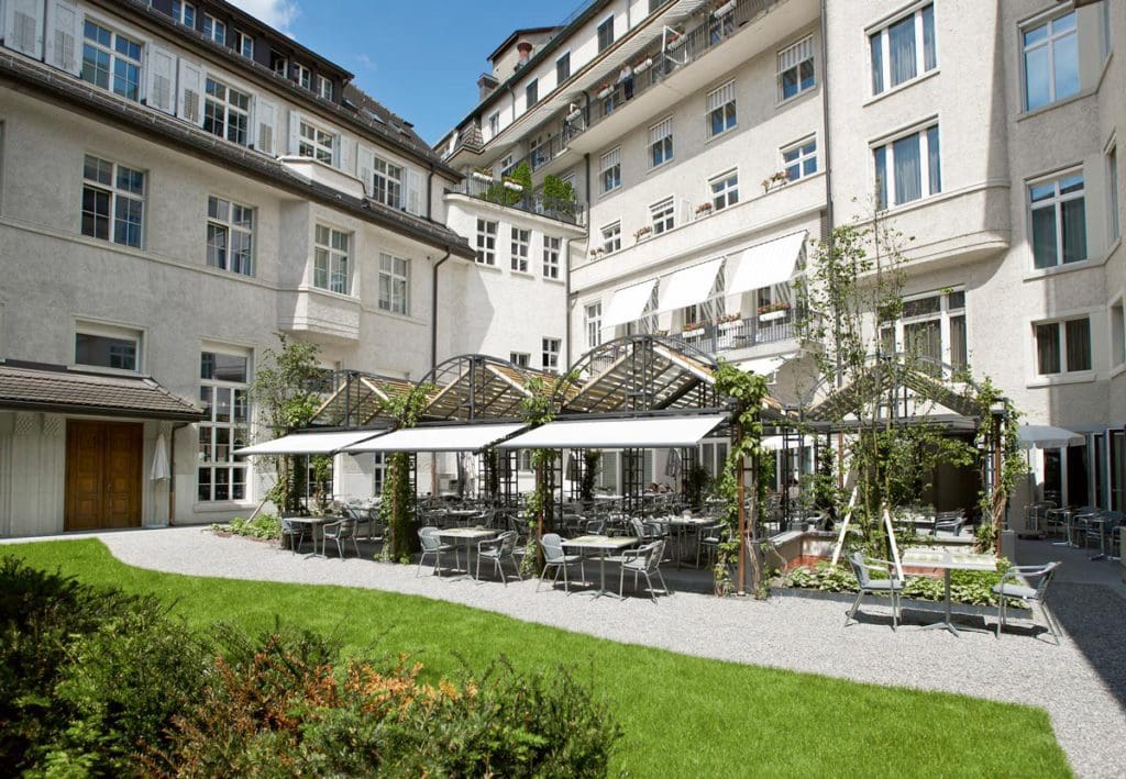 The lovely outdoor patio with a small green space inside a courtyard of Hotel Glockenhof.