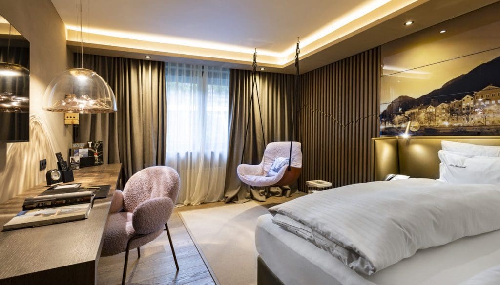 Inside one of the guest rooms at Hotel Innsbruck, featuring cool furnishings and a swing chair in the corner.