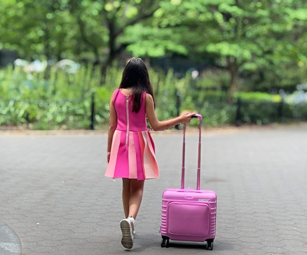 A young girl walks along a street with her BÉIS Kids Roller.