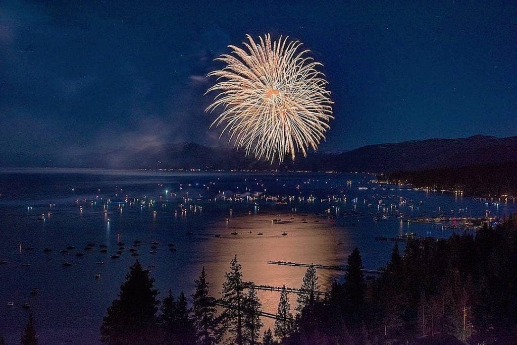 Fire works going off over Lake Tahoe, with boats enjoying the show below.