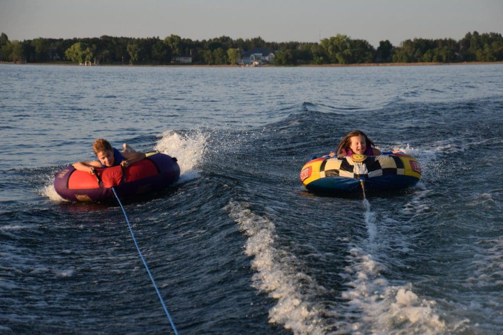 Two kids on tubes being pulled behind a boat on Otter Tail Lake.