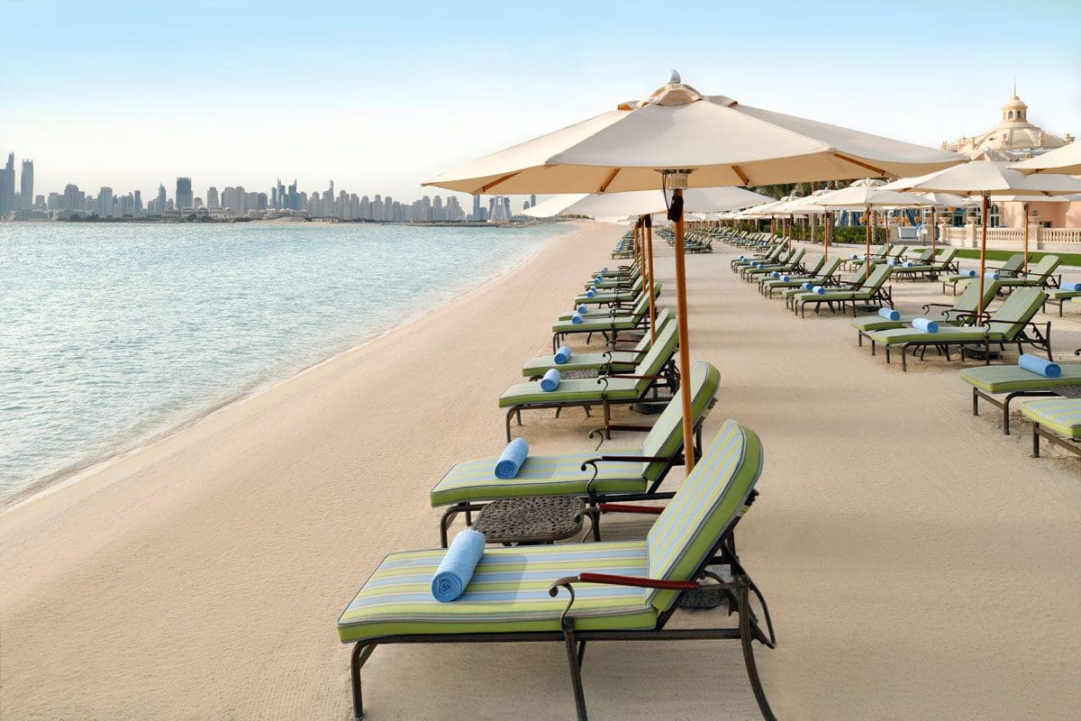 A line of beach chairs with umbrellas at Raffles The Palm Dubai.