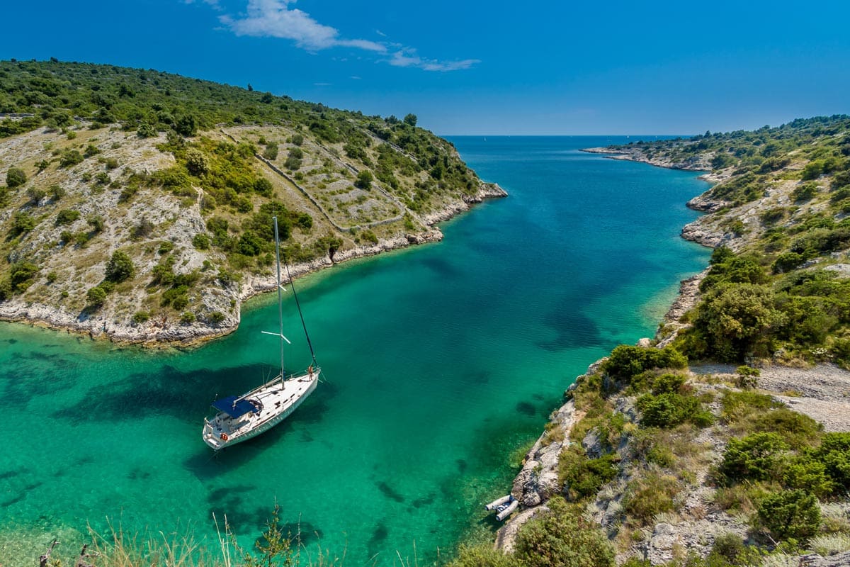 A boat leaves the port of Trogir in crystal-clear waters.