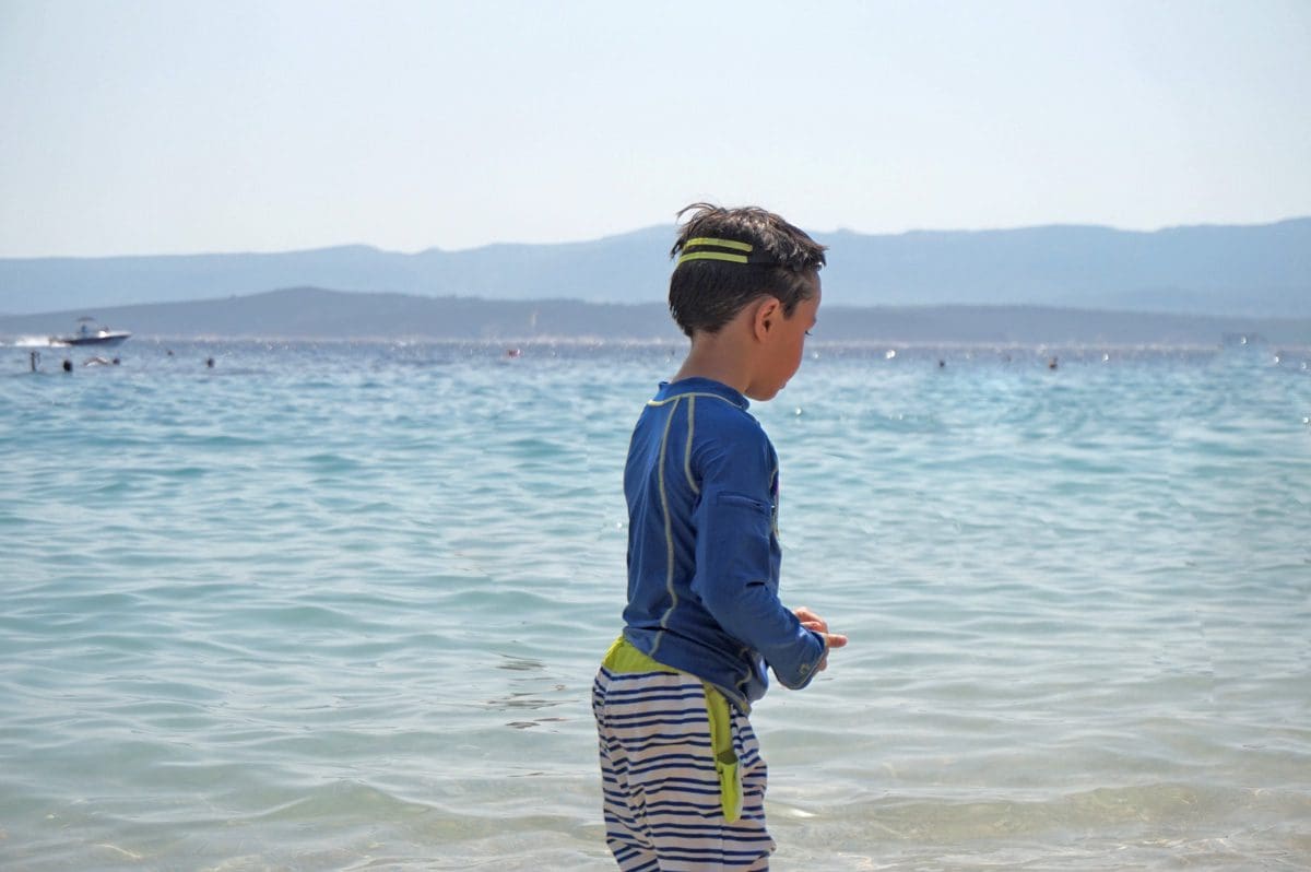 A young boy in a bathing suit walks toward the ocean near Brač.