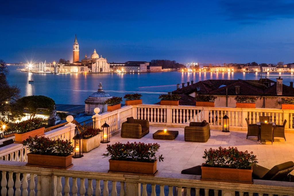 The outdoor rooftop of Baglioni Hotel Luna at night with a great view of the nearby town lights.