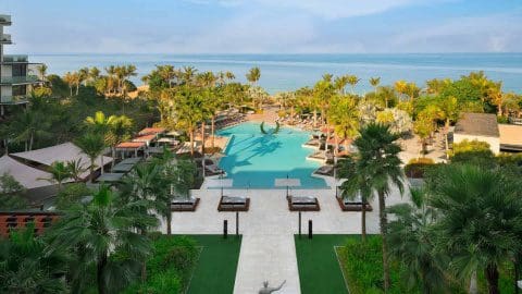 An aerial view of the pool, surrounded by palm trees, at Caesars Palace Dubai.