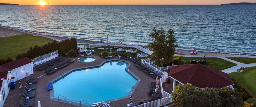 The outdoor pool at Inn at Bay Harbor, Autograph Collection, with a sunset over Lake Michigan in the distance.