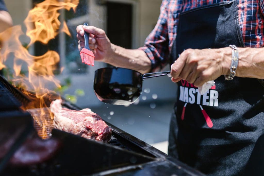 Close up of a man grilling meat.