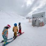 Three kids waiting to get onto a magic carpet while skiing in Kühtai.